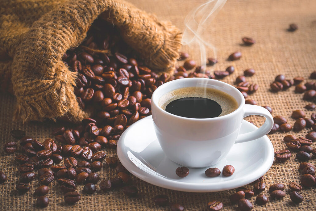 Een kopje naast koffiebonen — volledig ontwerp